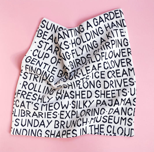 Knitted pillow with black text on a pink background