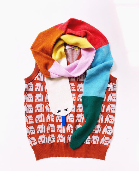 Colorful knitted lambswool snake scarf draped over a patterned sleeveless knit vest with geometric house pattern on a white background