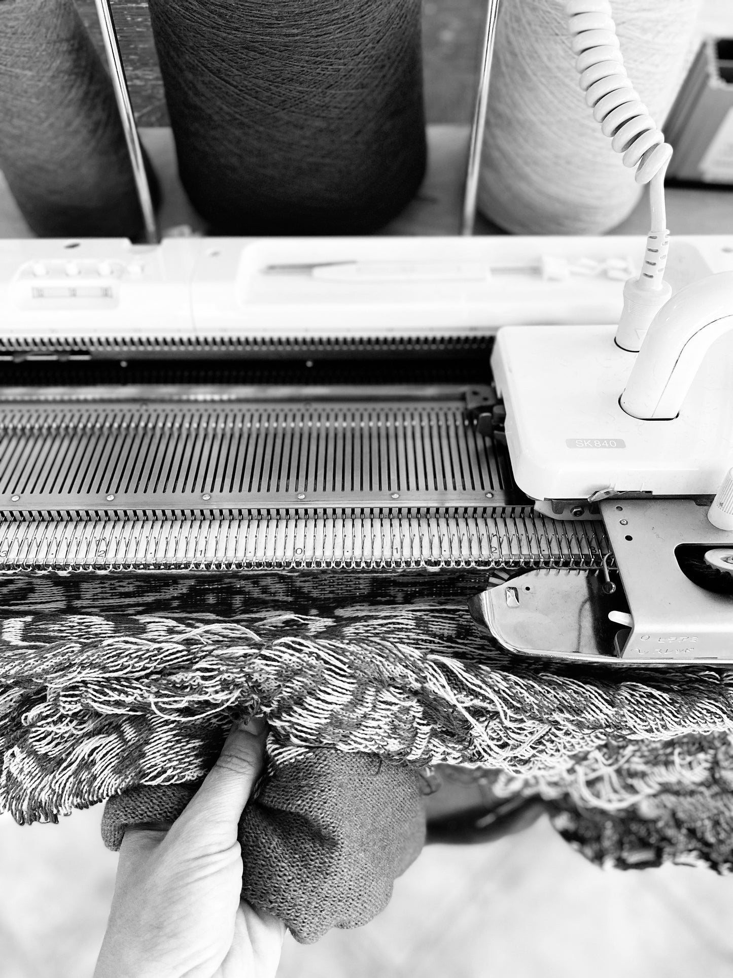 Knitting machine with fabric being woven, close-up view.