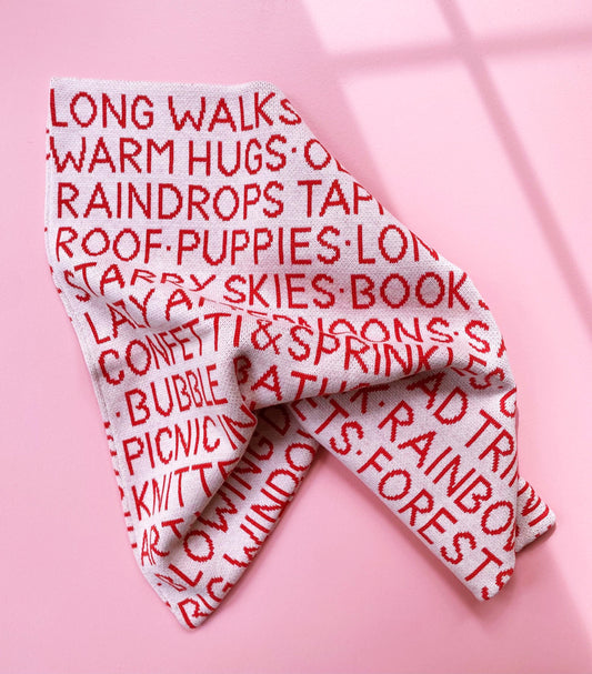 Folded blanket with red text on a pink background