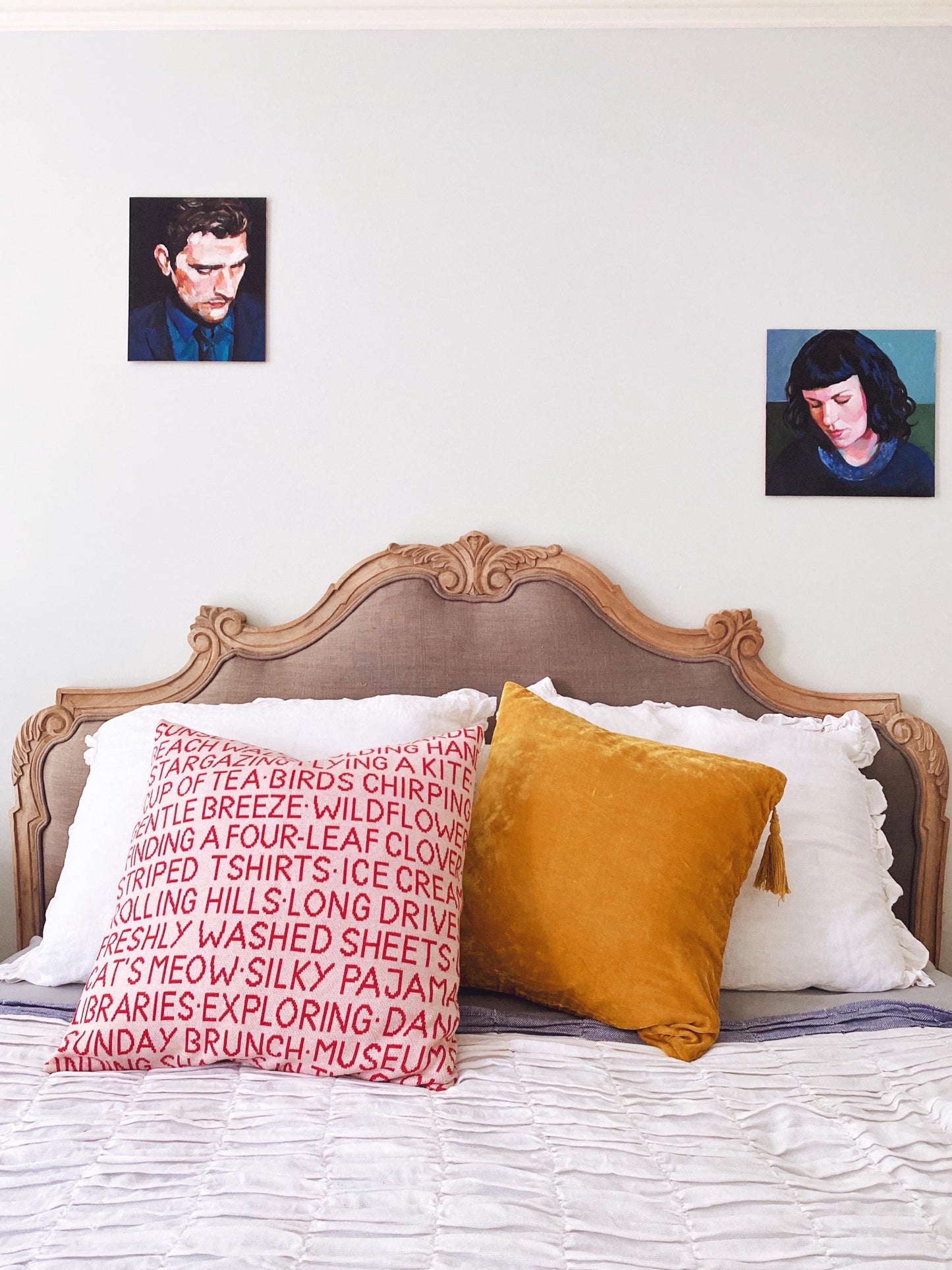 Bedroom with wooden headboard, decorative pillows, and wall art.