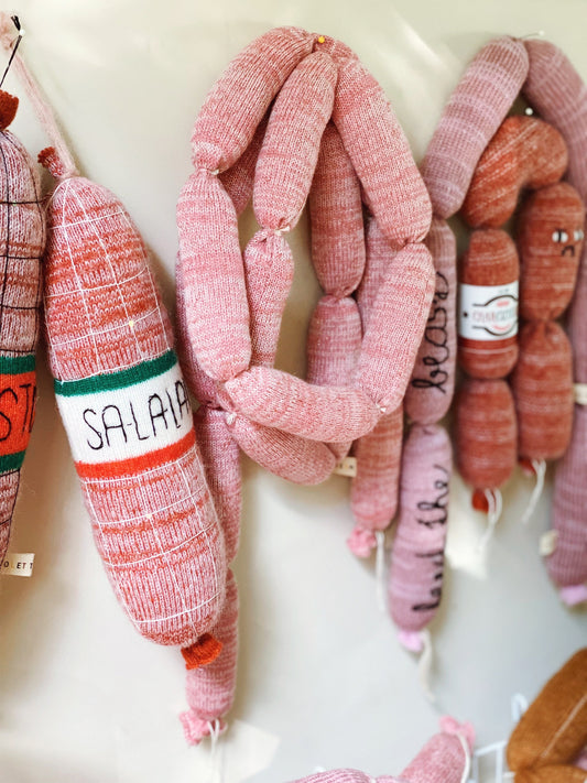 Soft knitted sausage links with visible branding on a white background