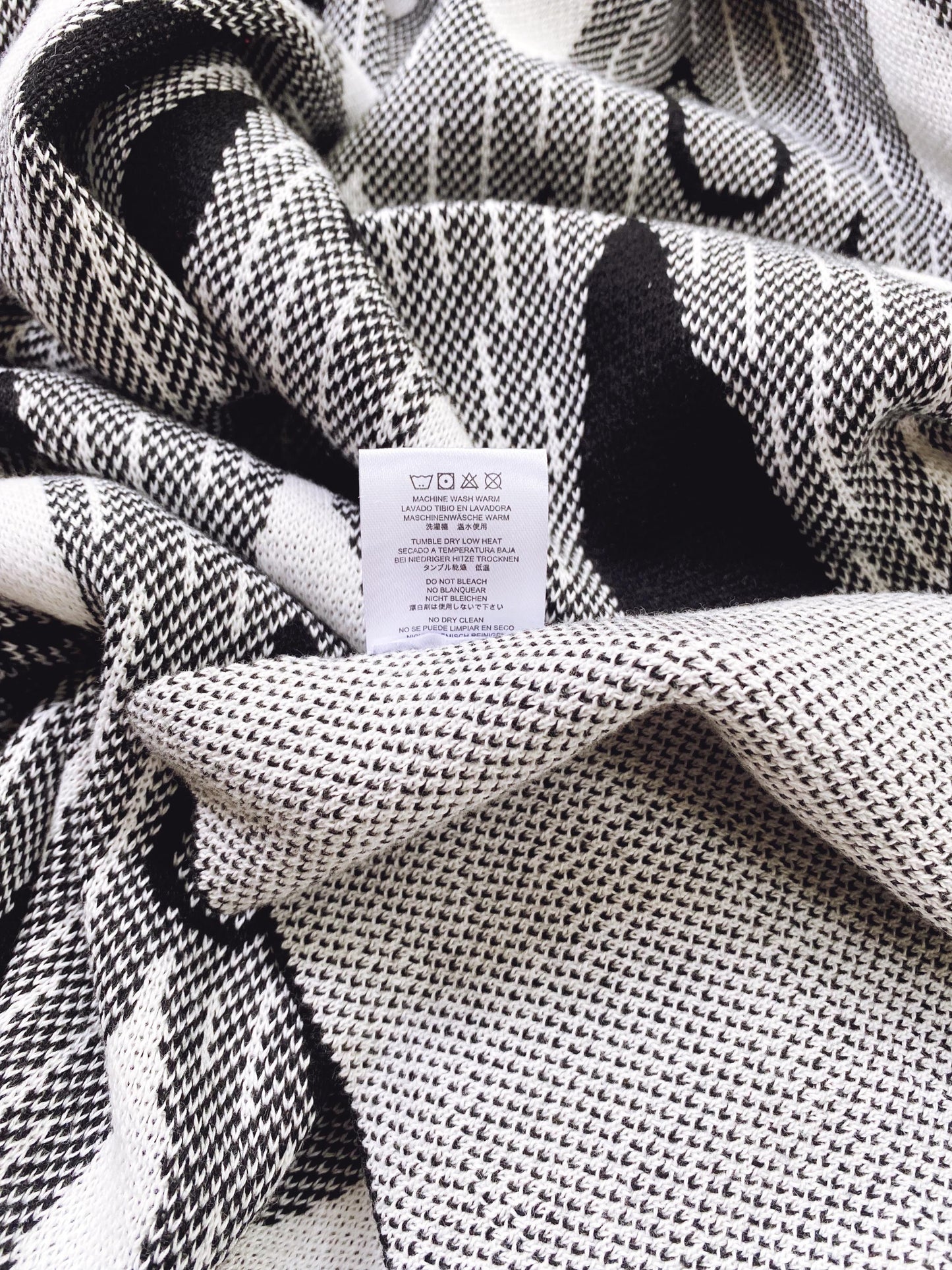 Close-up of a knitted black and white patterned fabric with a label.