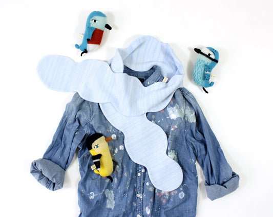 Blue denim shirt with cartoon character plush toys and a blue cloud shaped scarf on a white background