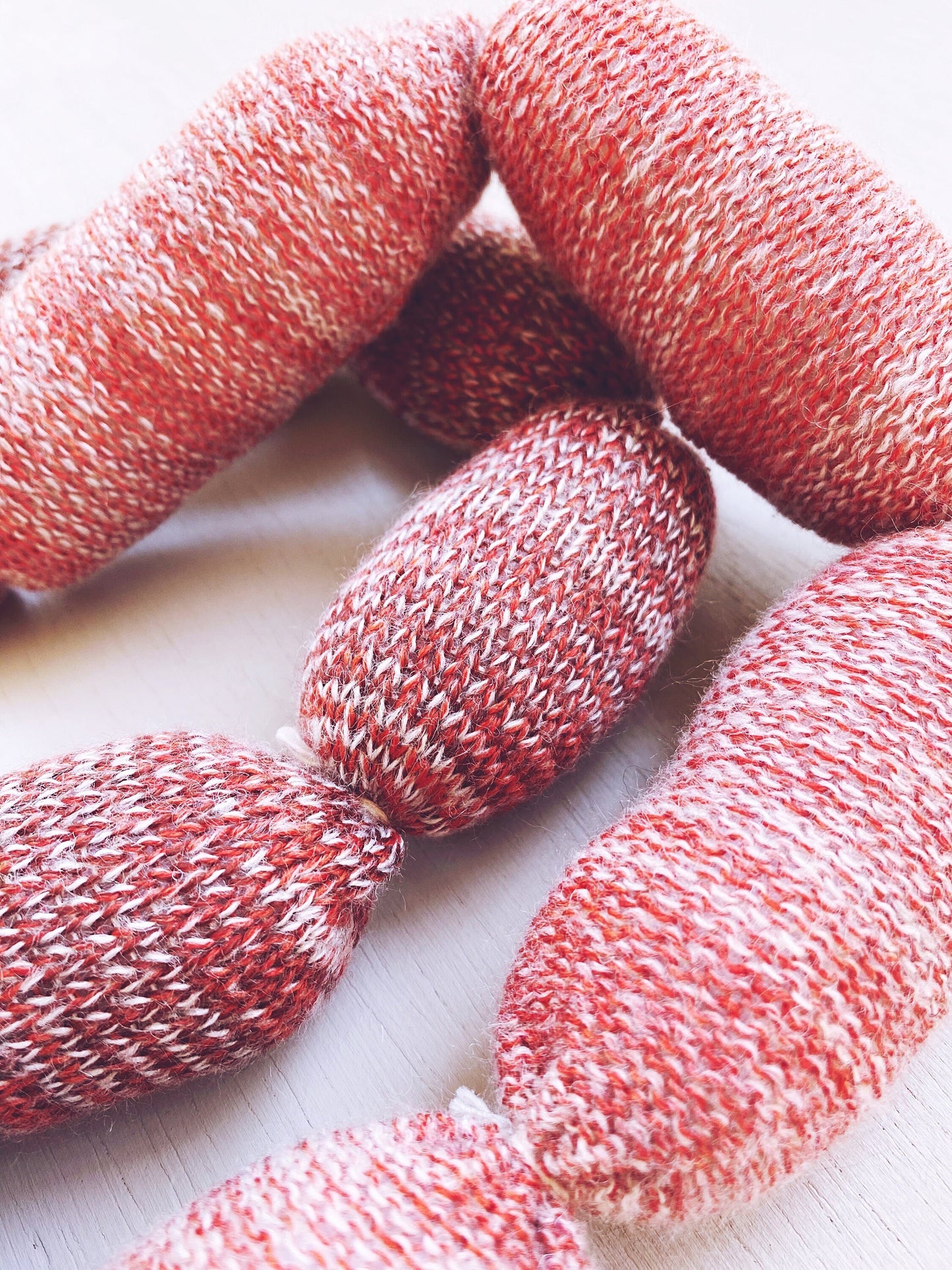 Handmade knitted sausage on a light wooden surface