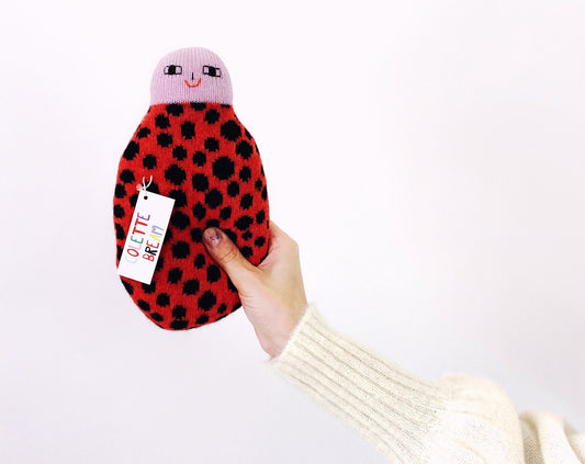Hand holding a plush ladybug toy with a white background