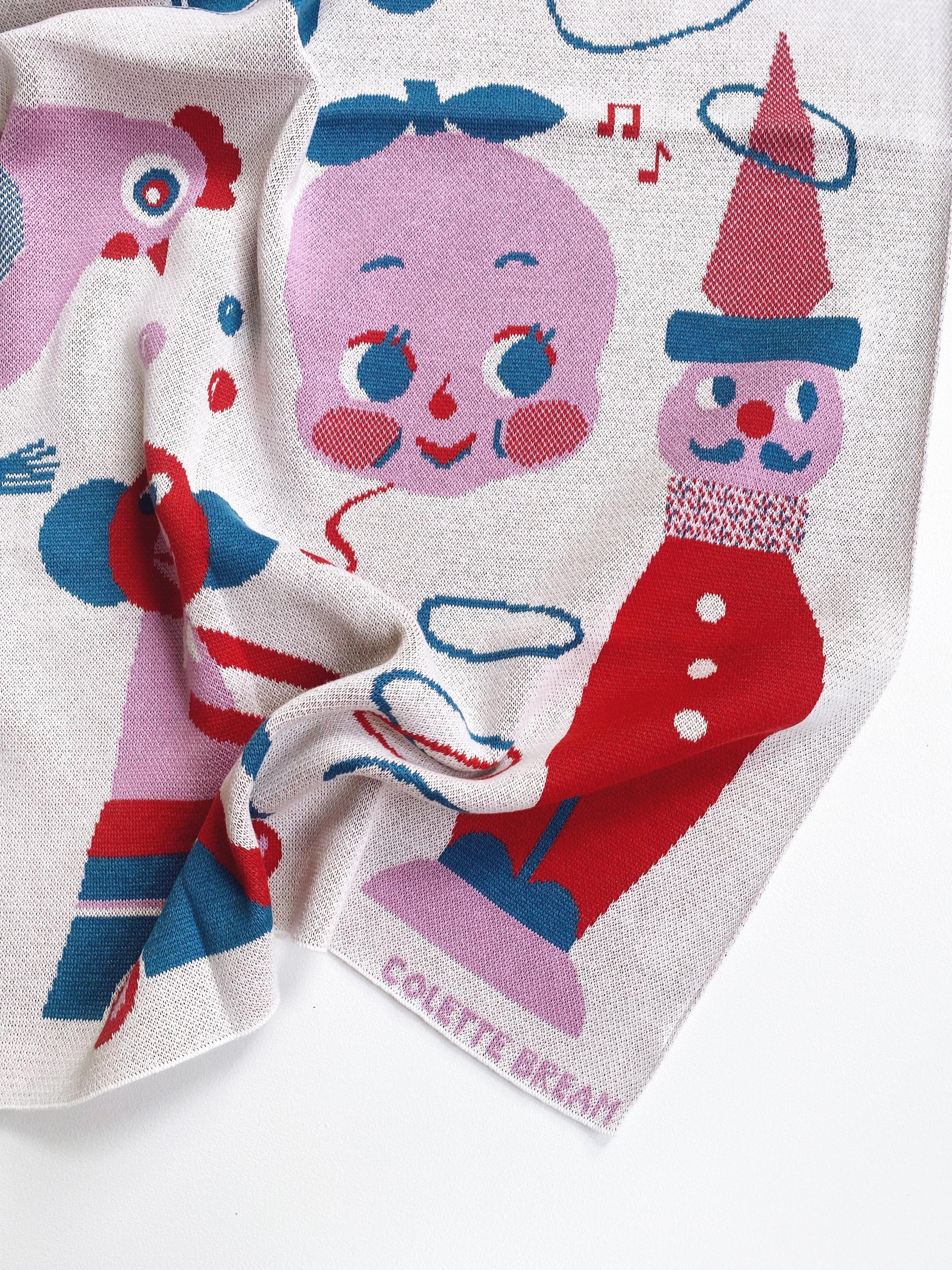 Colorful knitted baby blanket with cartoon characters and 'Colette Bream' branding.