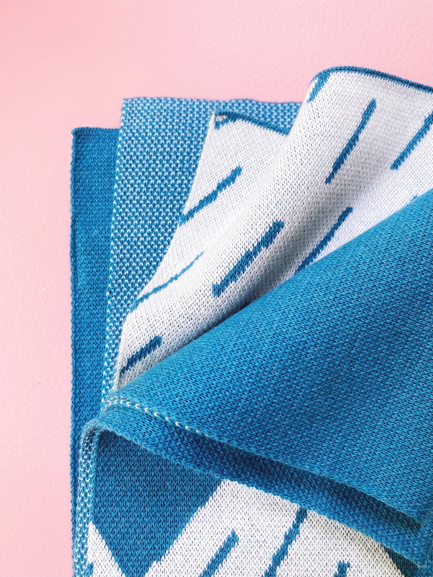 Blue and white patterned knit fabric on a pink background