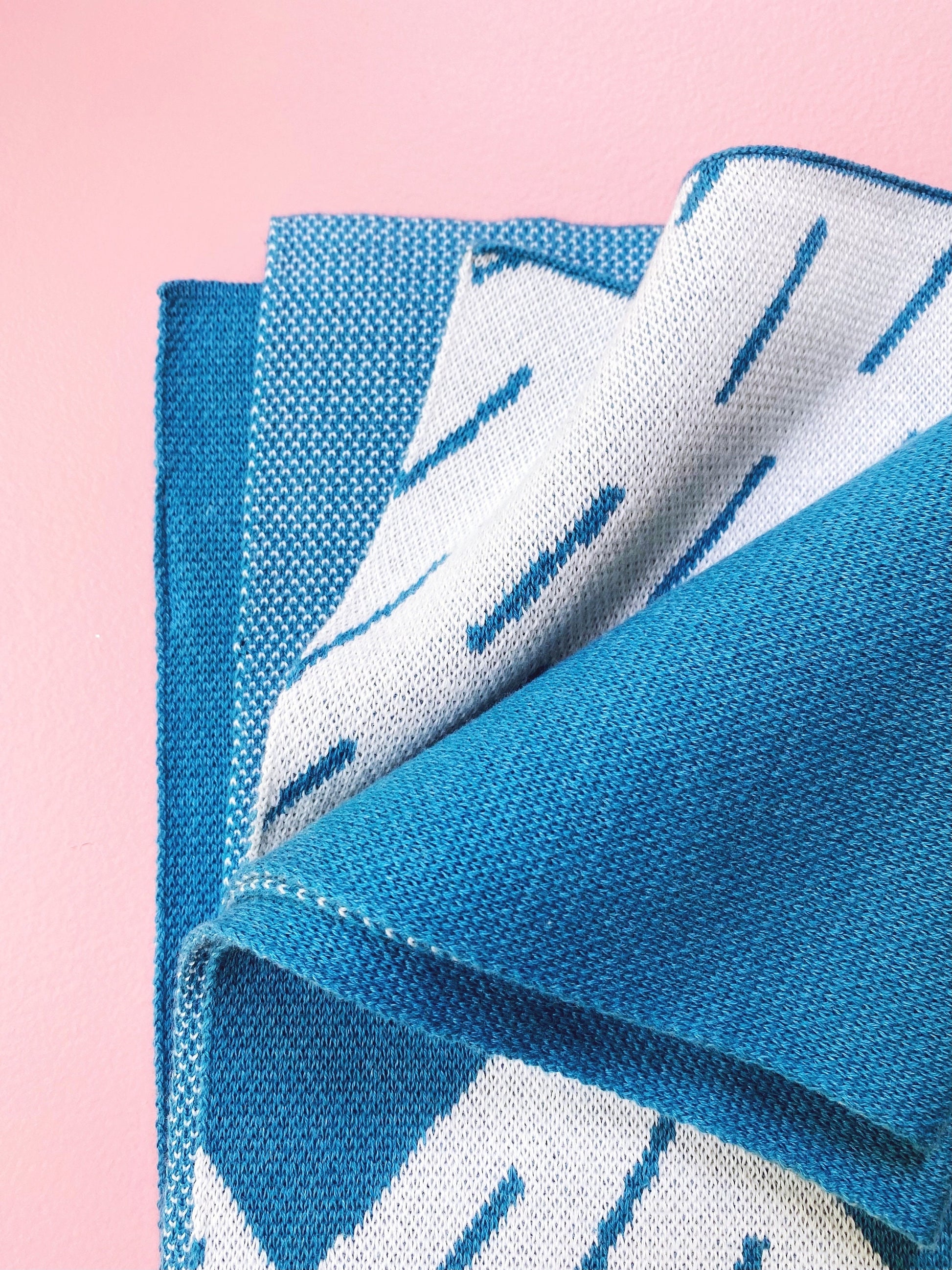 Blue and white patterned knit fabric on a pink background