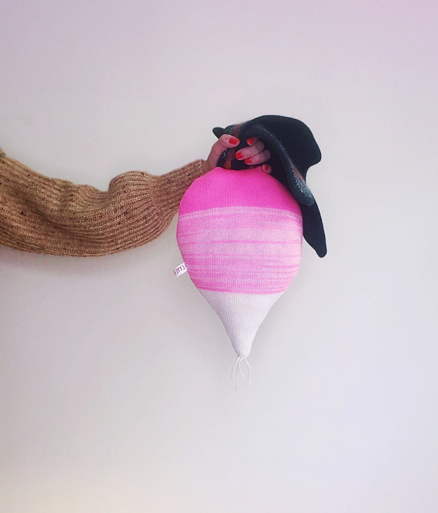 Decorative knitted pillow resembling a radish.