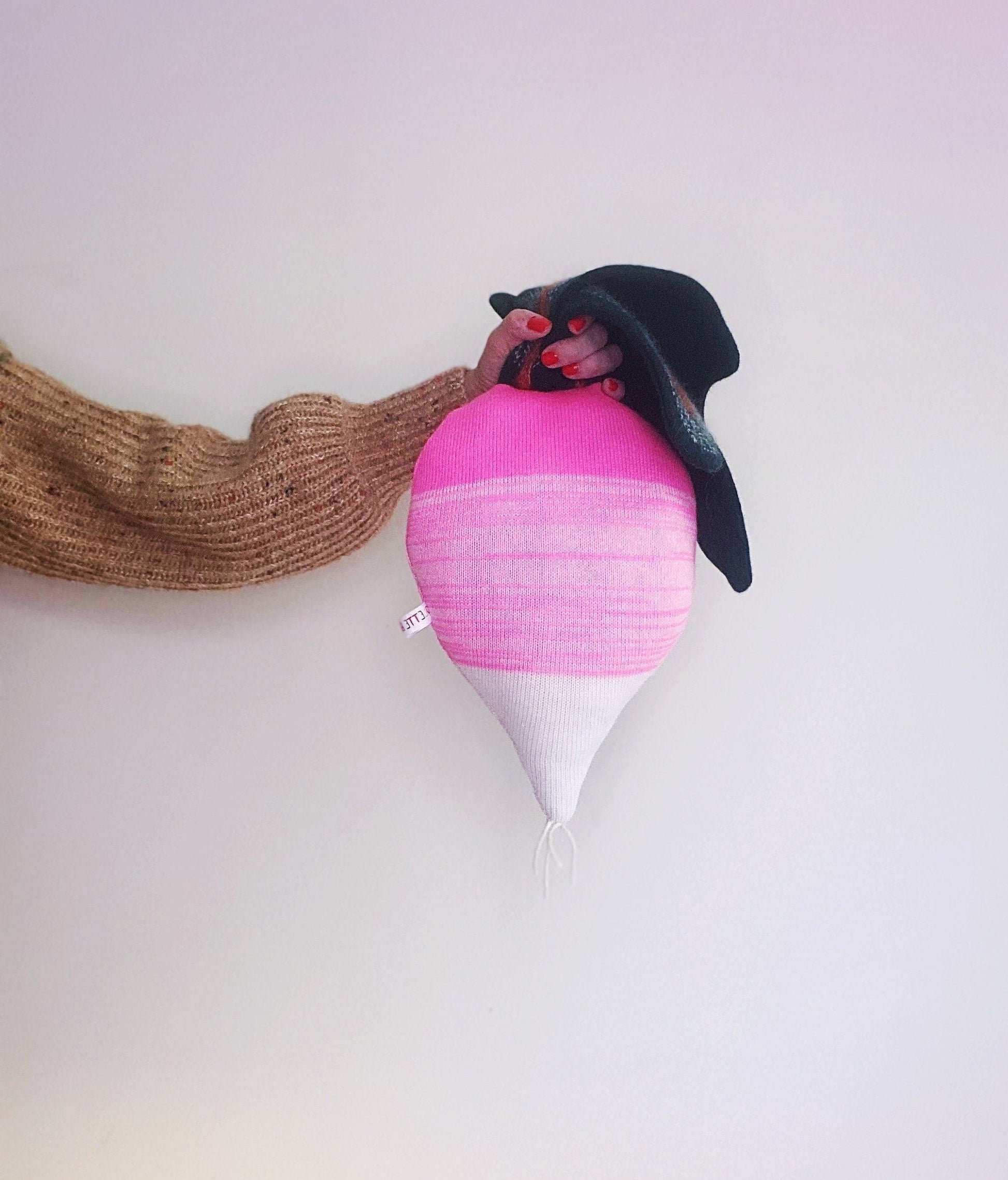 Decorative knitted pillow resembling a radish.