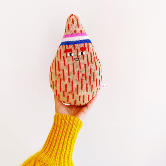 Hand holding a colorful knitted lambswool toy resembling a coconut cartoon character on a white background