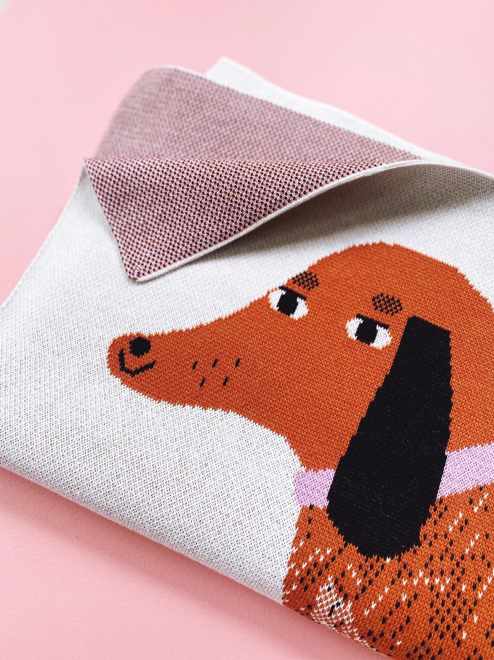 Detail of a knit fabric with a dachshund design on a pink background