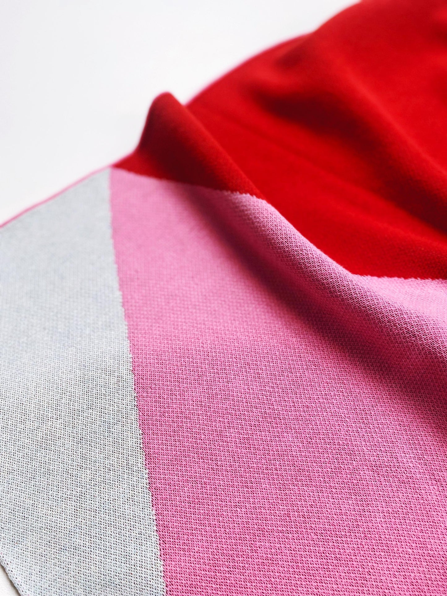 Close-up of knitted fabric with red, pink, and gray colors.
