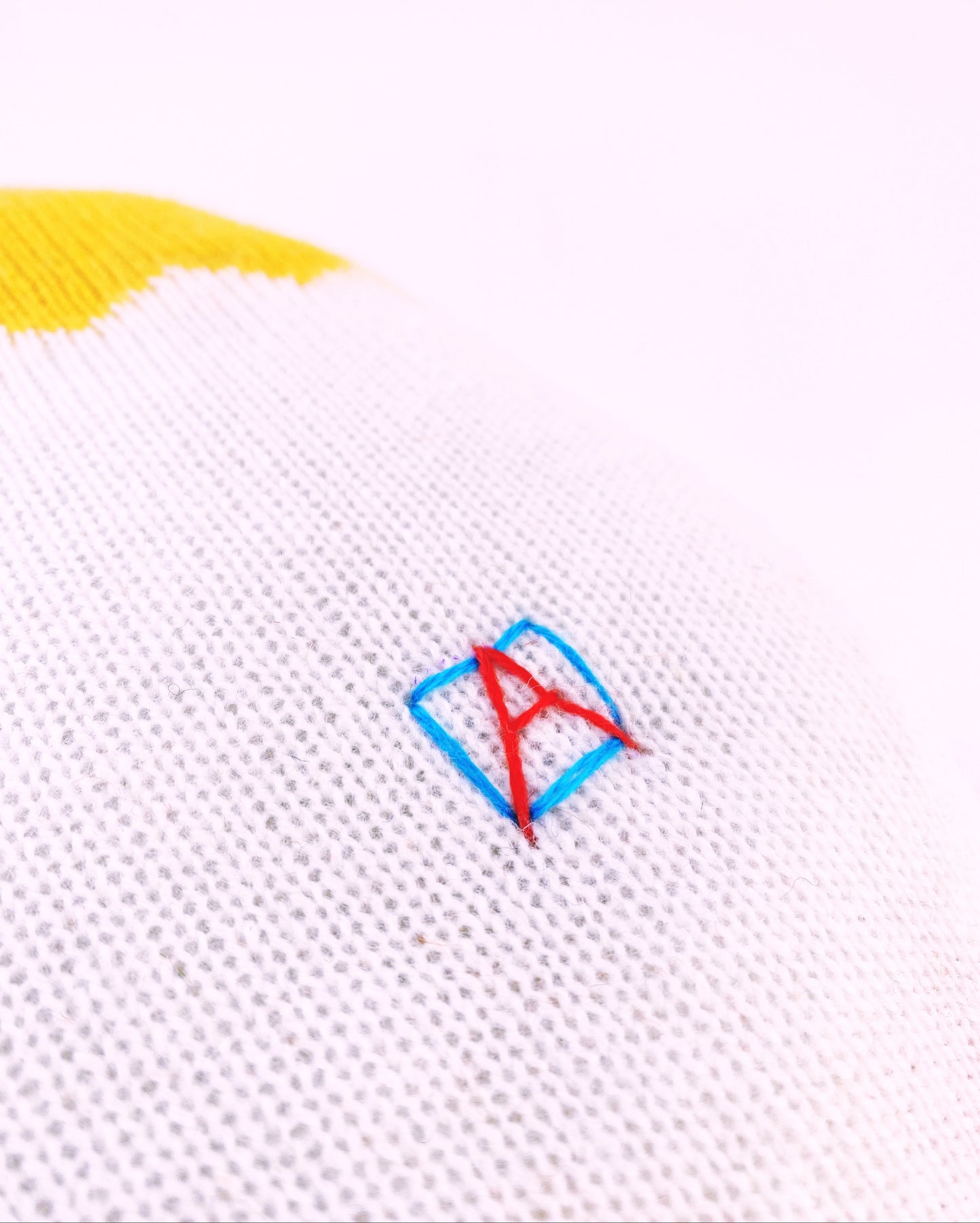 Close-up of a white knit fabric toy with a colorful logo on a white background