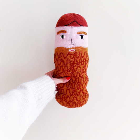 Knitted lambswool plush with a face and beard design held by a person against a white background