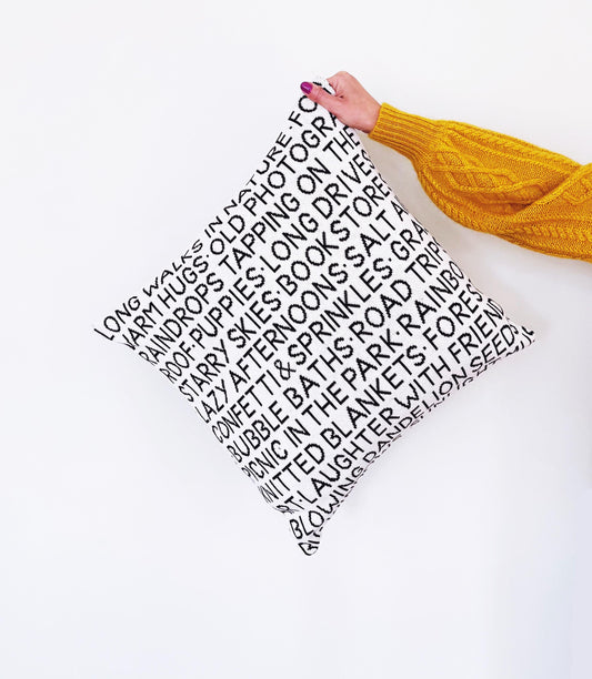 Person holding a wordy knitted pillow with text on a white background