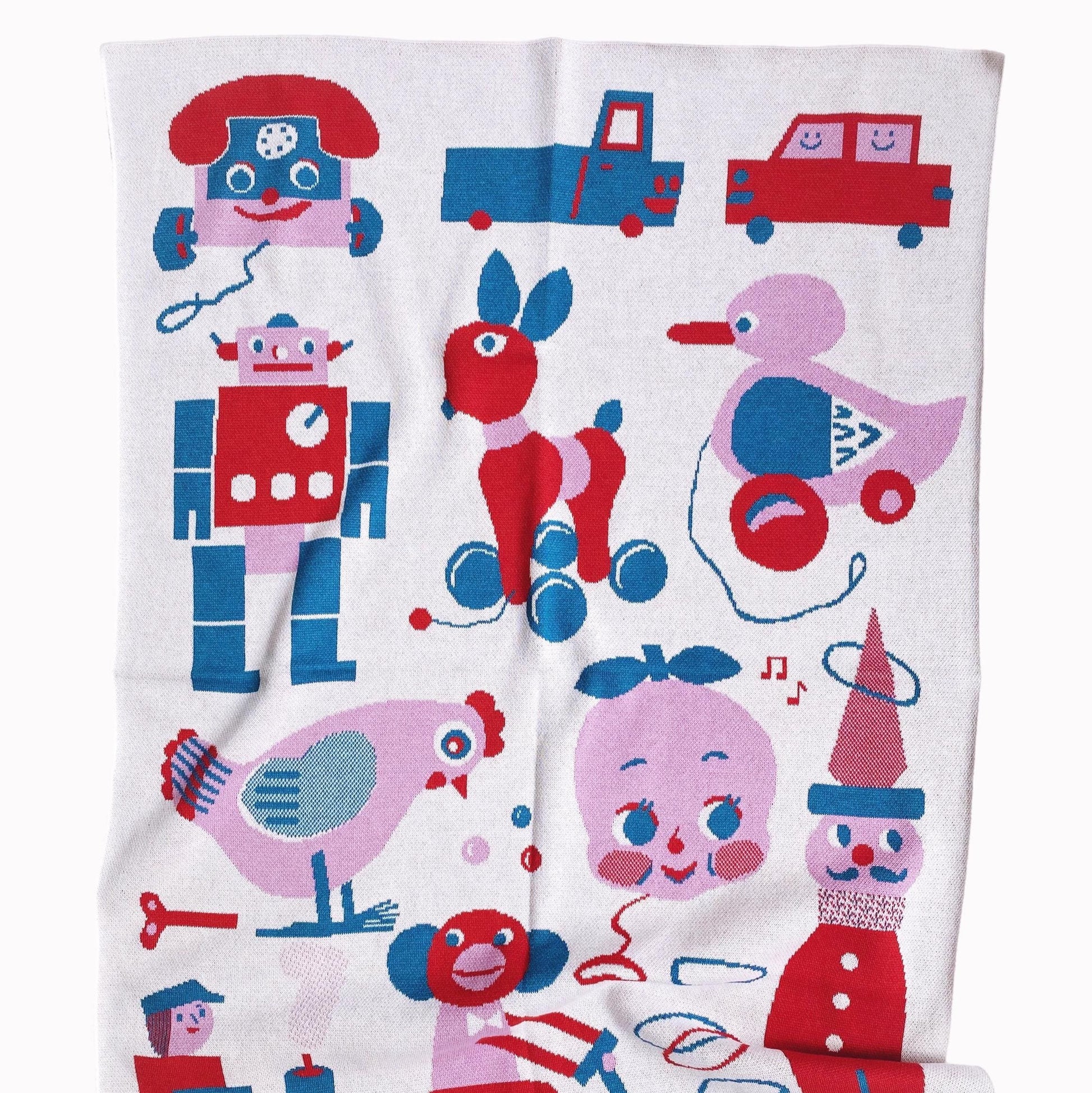 Children's knit blanket with colorful toy-themed design on a white background