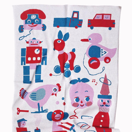 Children's knit blanket with colorful toy-themed design on a white background