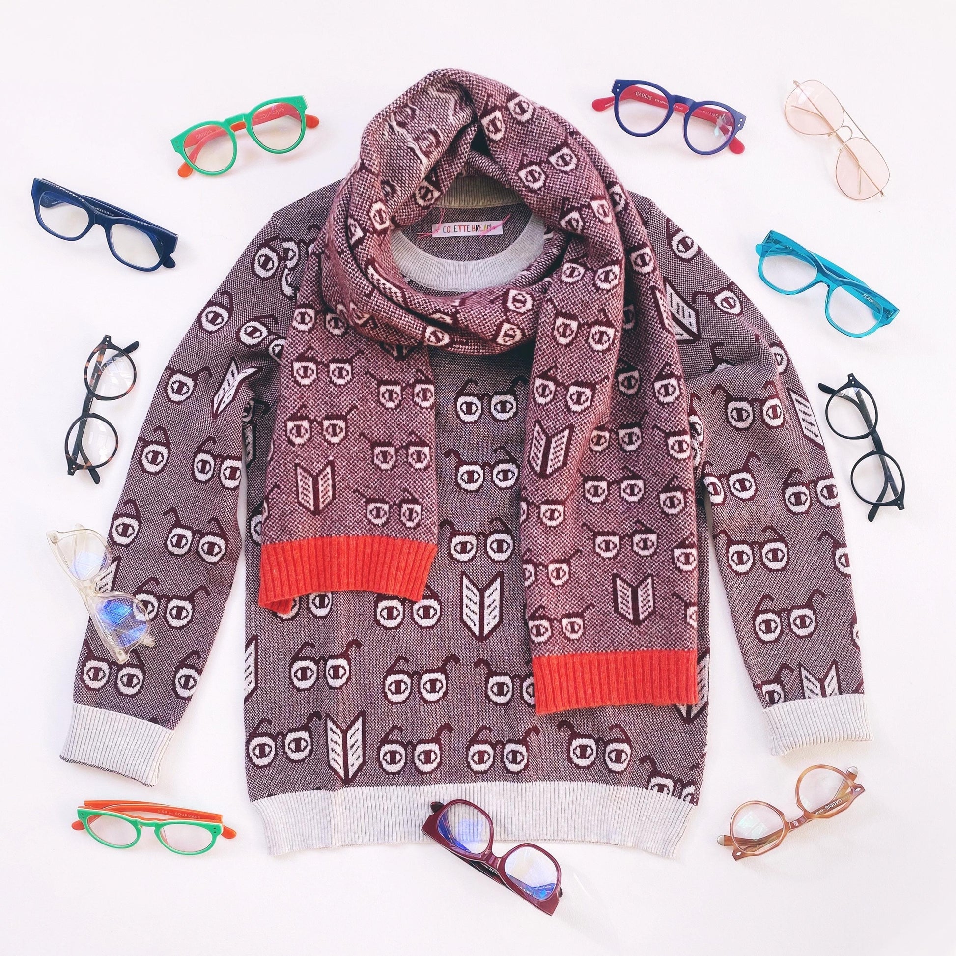 Patterned sweater with red accents surrounded by colorful spectacles eyeglasses on a white background