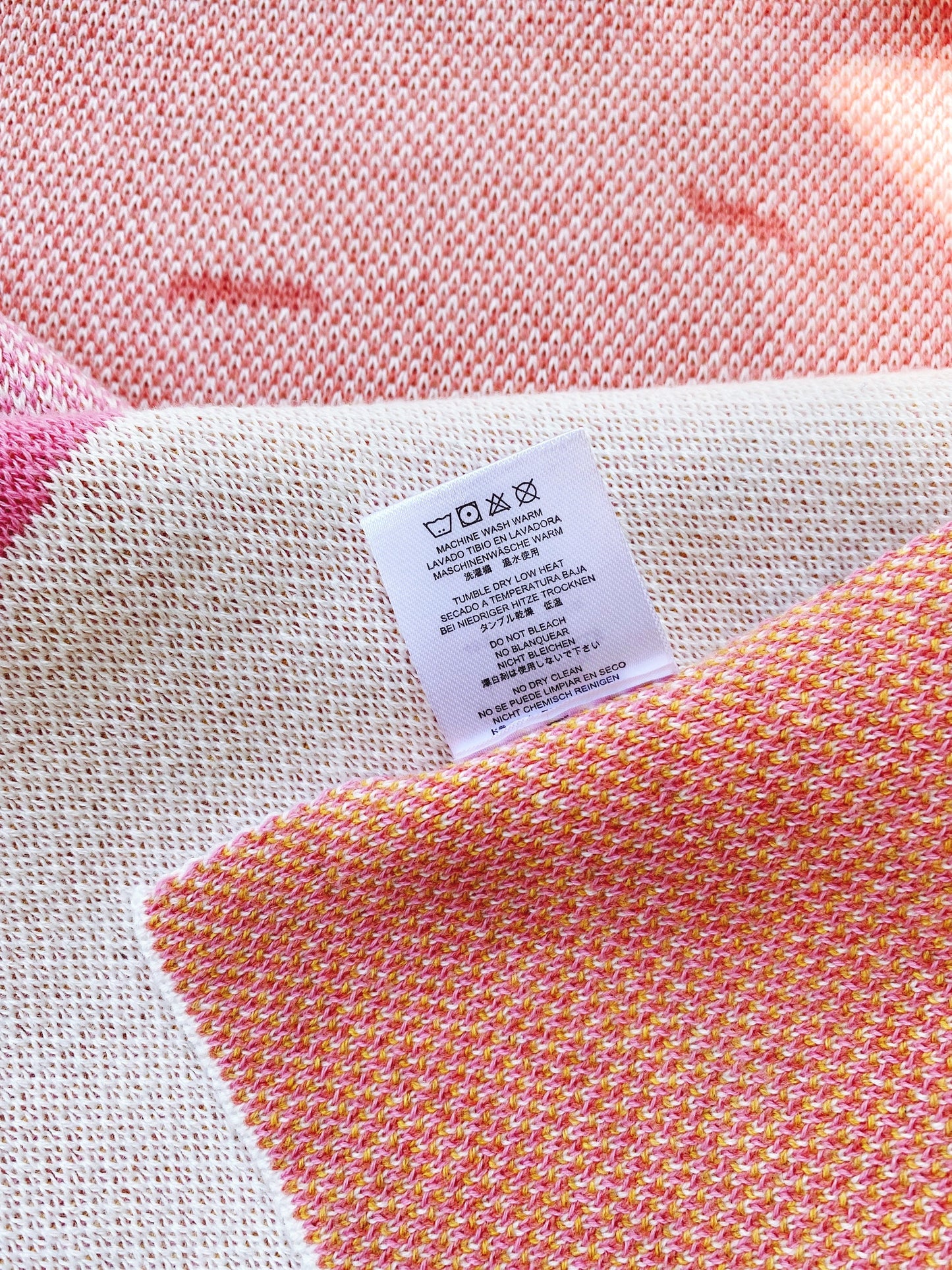 Close-up of a knit fabric with a label on a pink and white patterned background