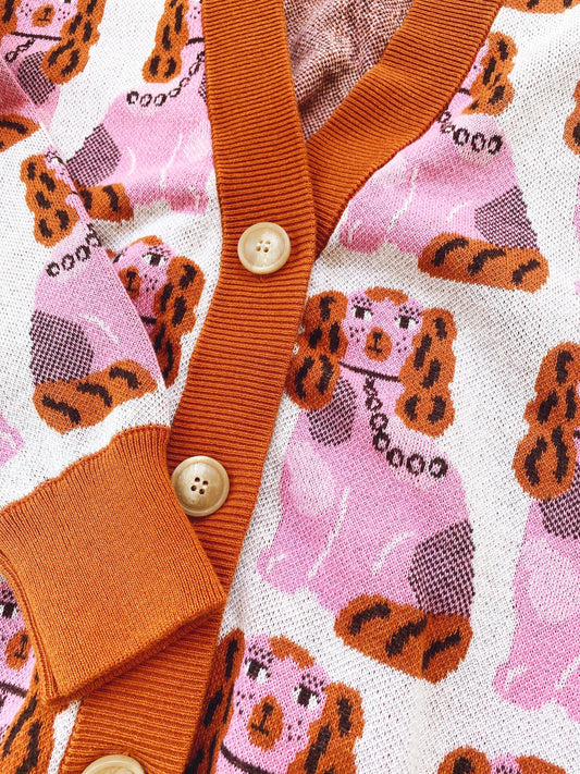 Close-up of a knitted cardigan sweater with a pink pattern featuring cartoon of staffordshire dogs and buttons.