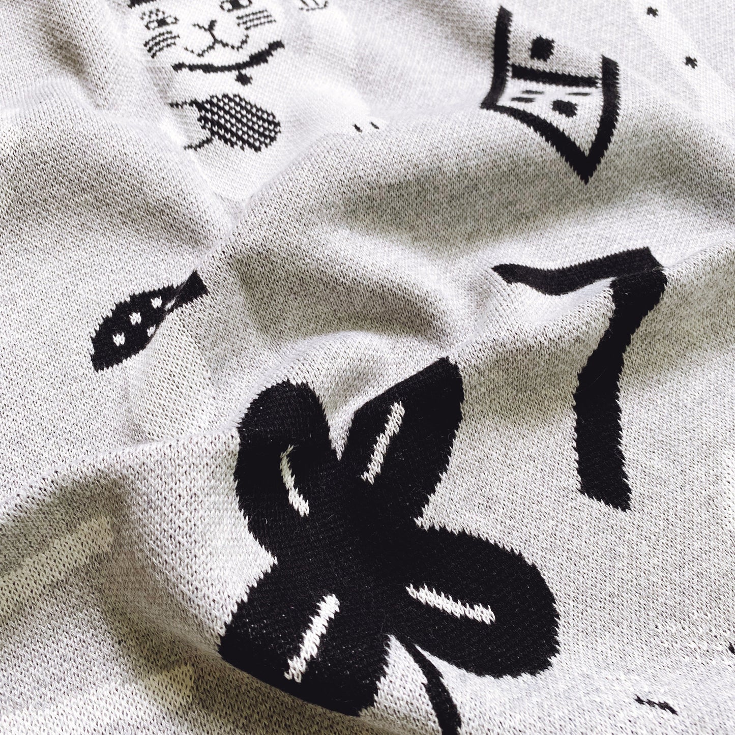 Close-up of a knitted blanket fabric with lucky charms pattern designs on a white background