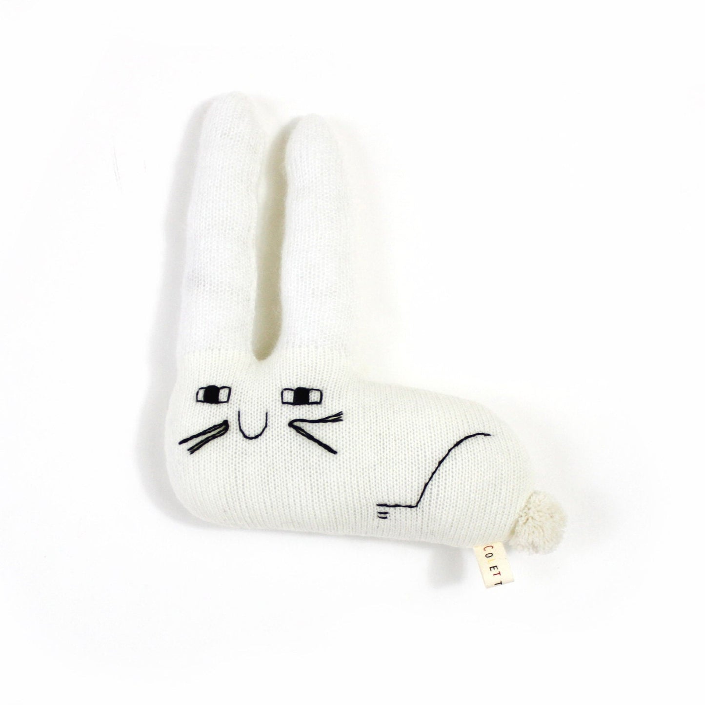 White knitted bunny shaped plush toy with happy face design on a white background