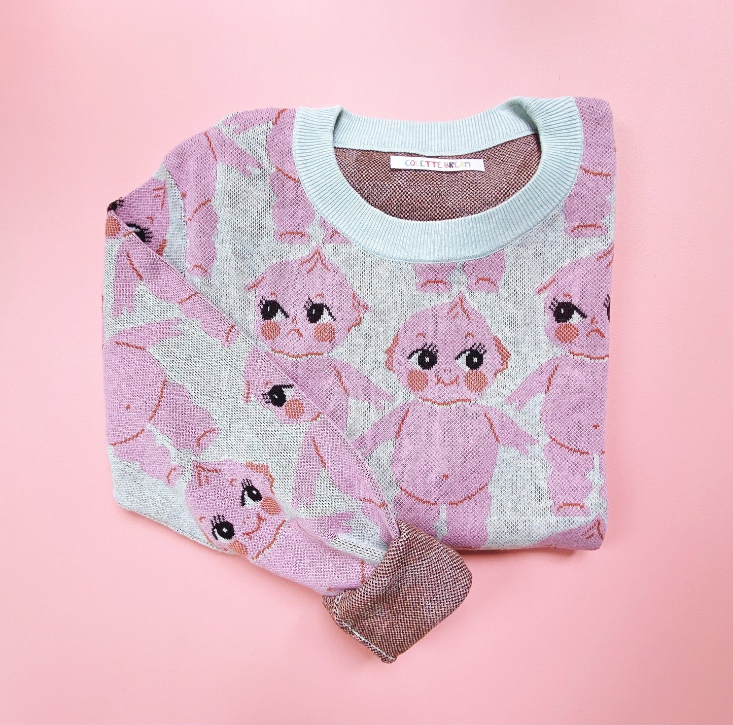 Knit sweater with pink kewpie doll pattern on a pink background