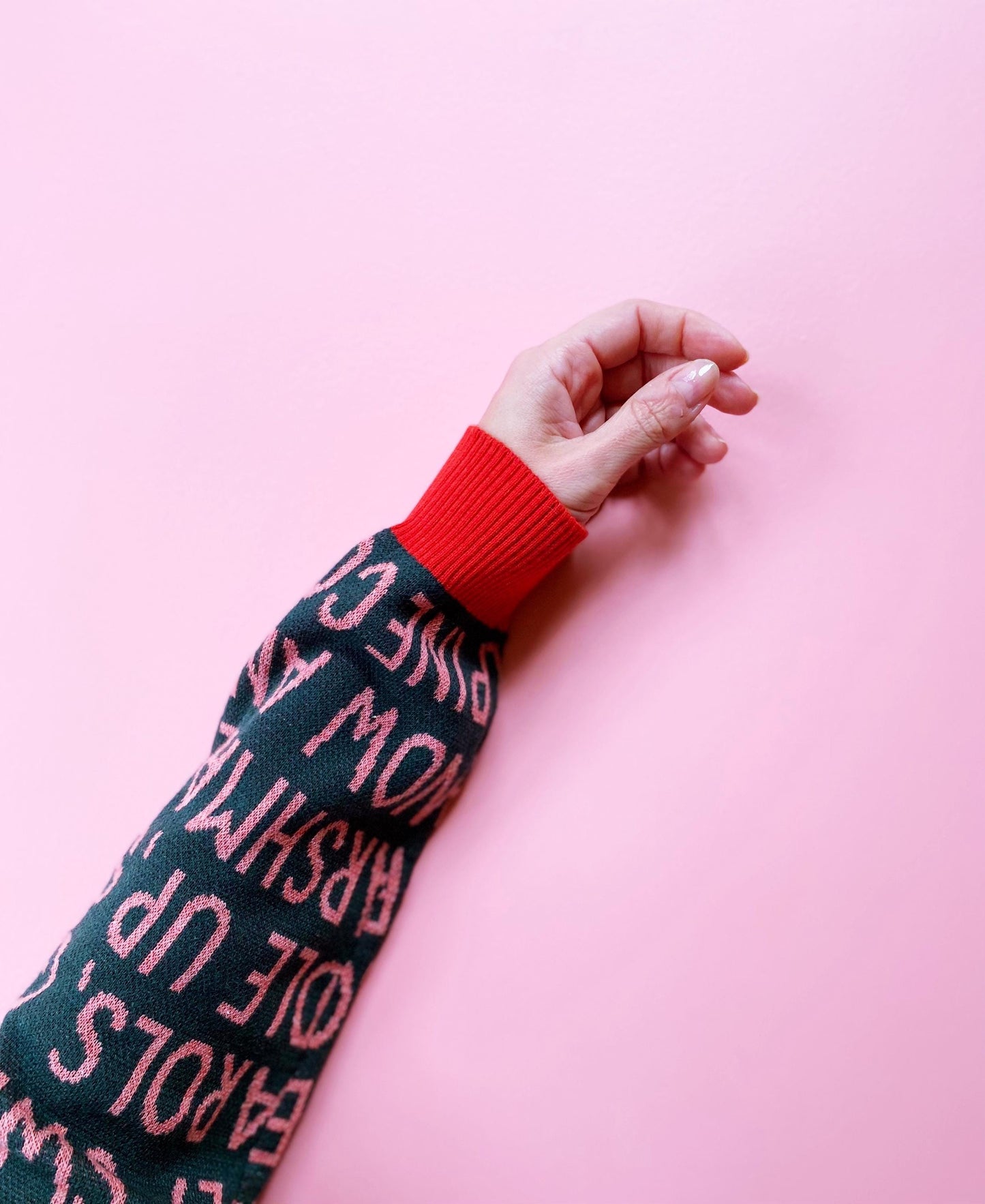 Person wearing a dark green sweater with red text on a pink background