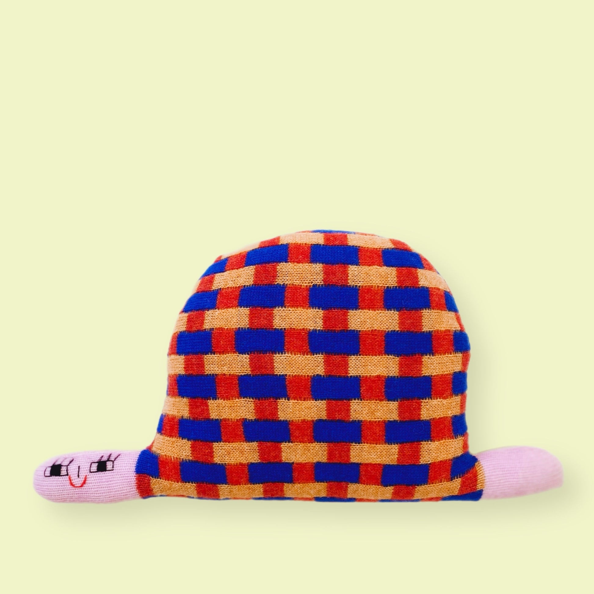 Knitted turtle character with pink accents on a light yellow background