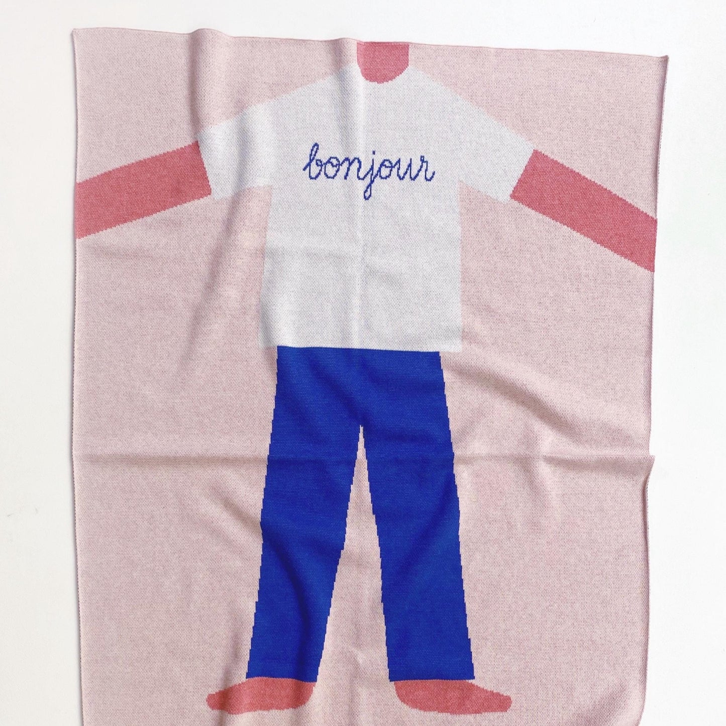 Knit blanket with a cartoon boy character wearing a white shirt and blue pants on a pink background