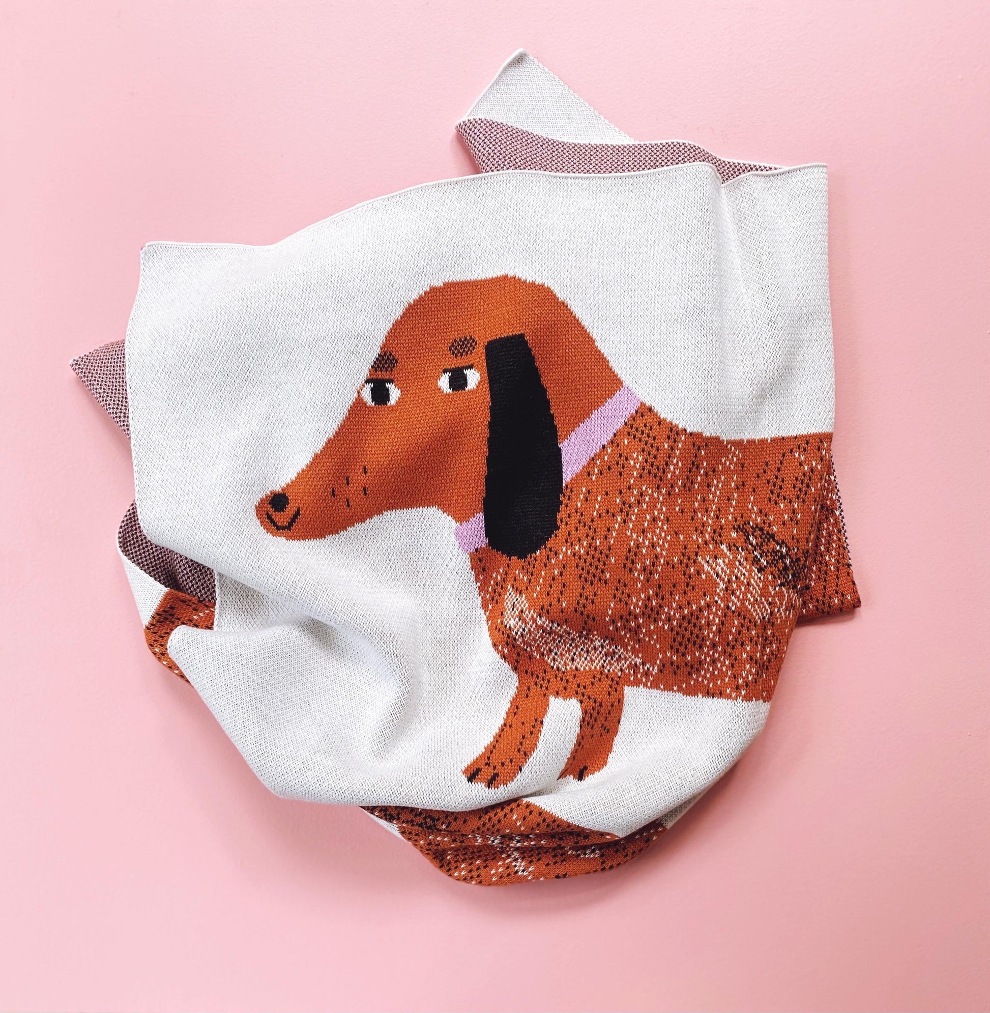 Detail of a knitted fabric blanket with a dachshund design on a pink background