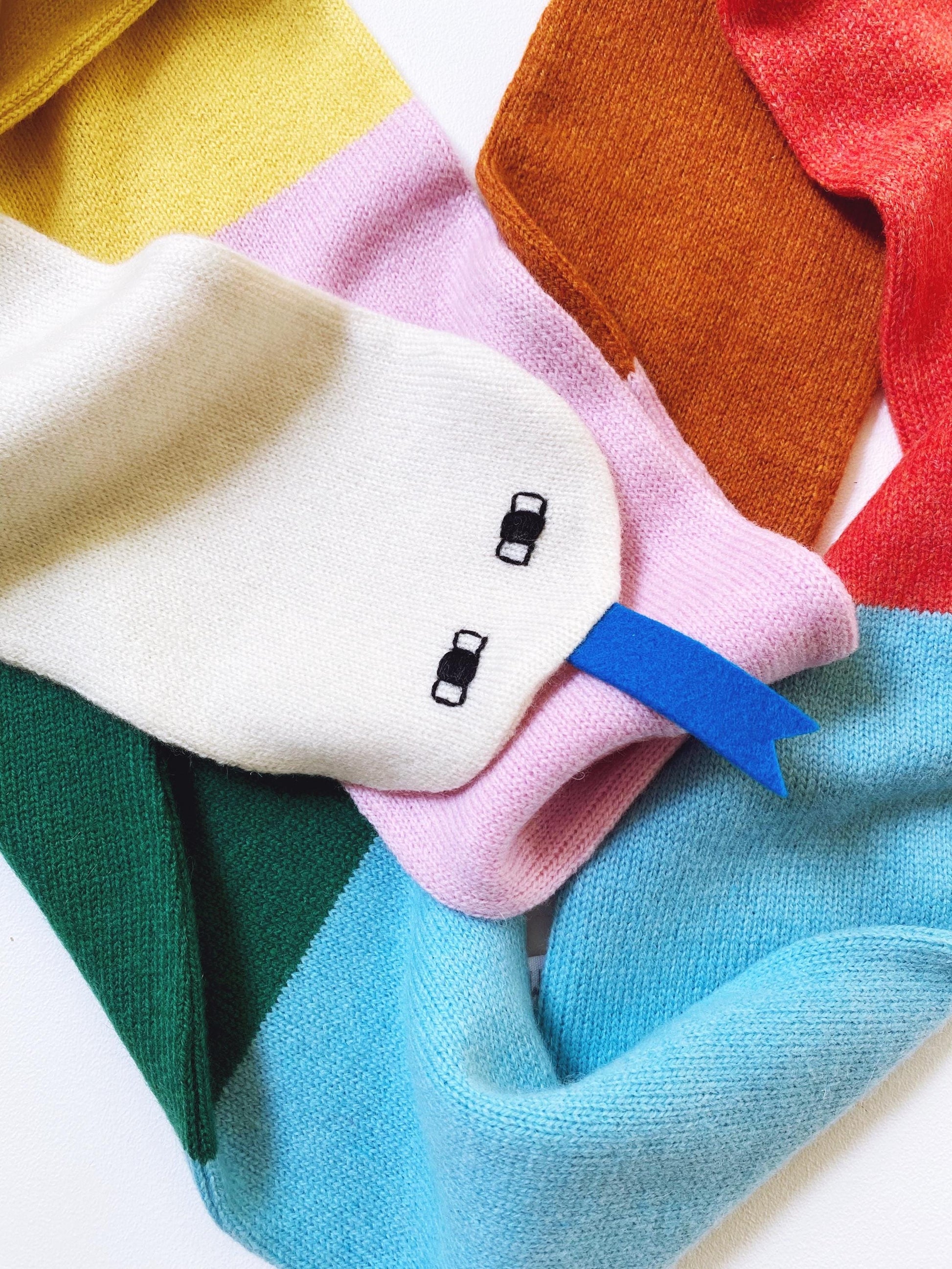 Colorful folded knitted scarf shaped like a snake on a white background