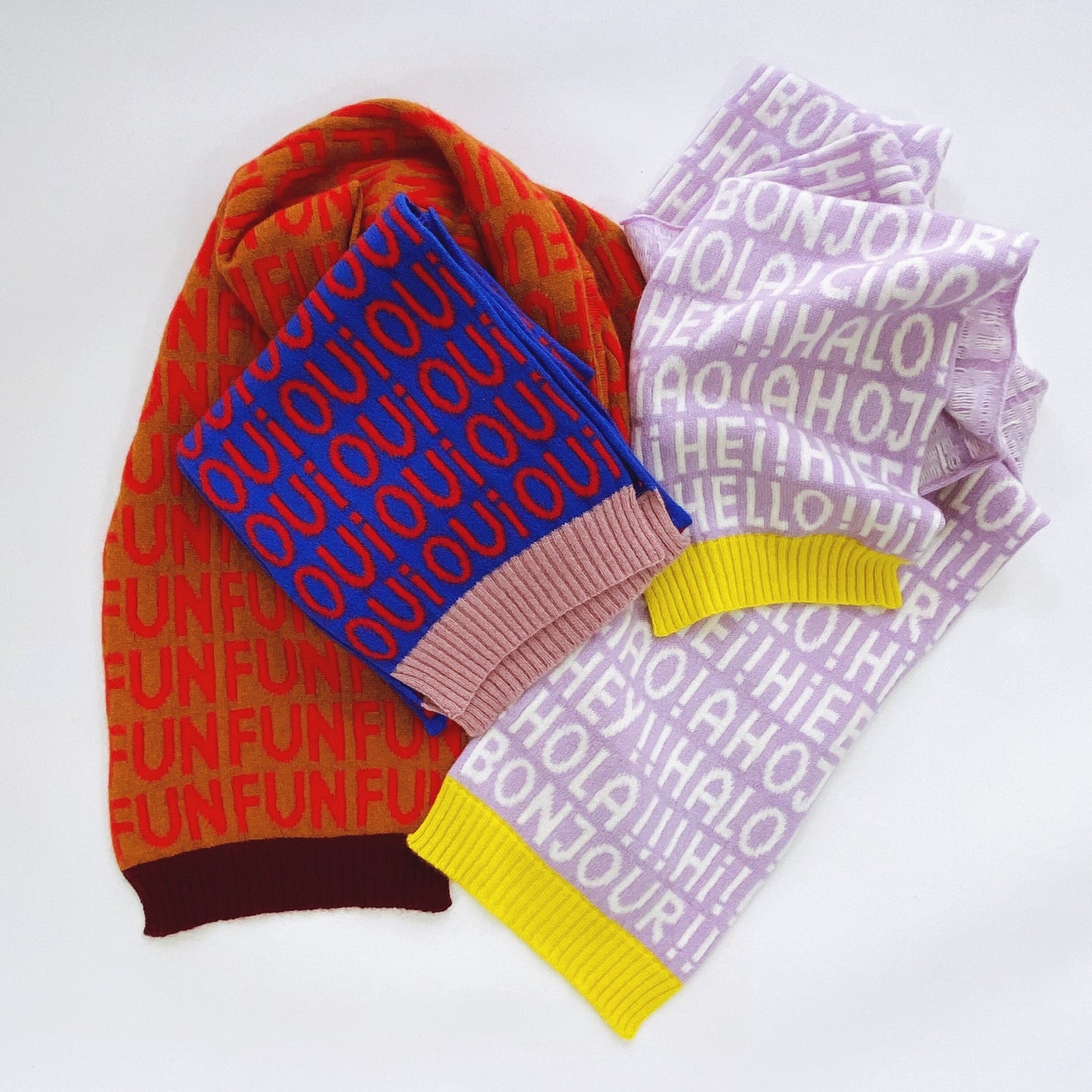 Colorful knitted scarves with text patterns on a white background