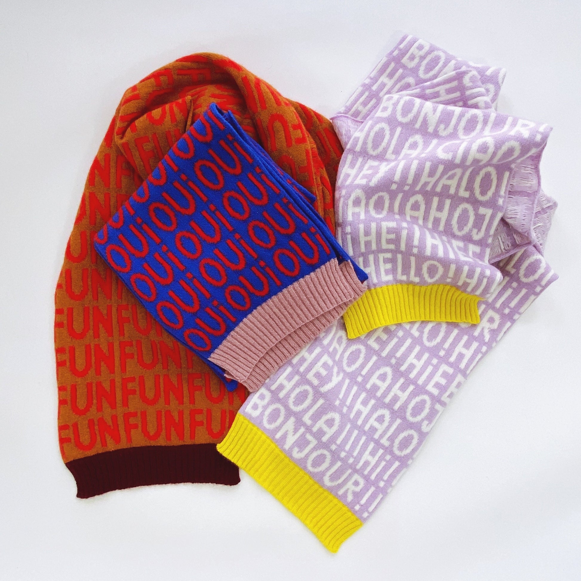 Colorful knitted scarves with text patterns on a white background