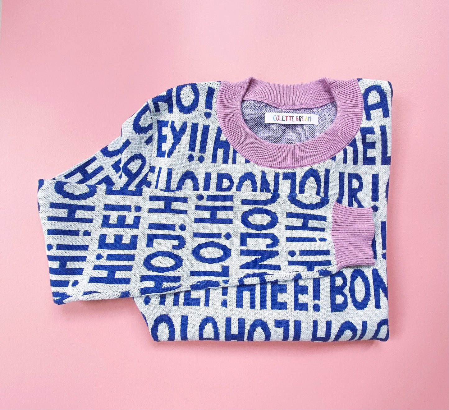 Folded sweater with blue text on a pink background