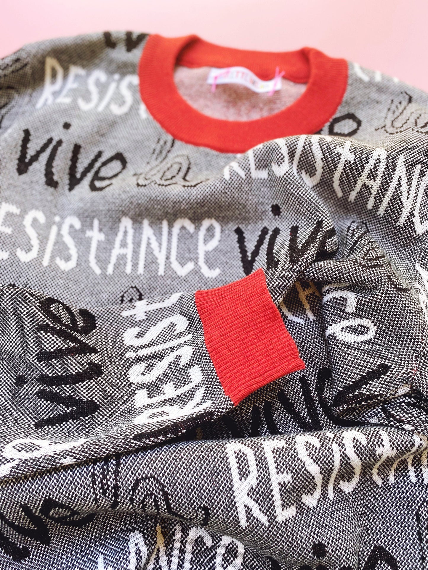 Black and white sweater with 'Vive la Resistance' text, red trim, collar and cuffs.