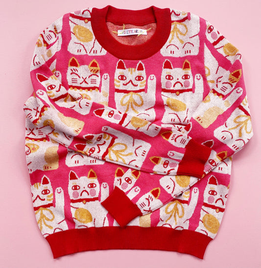 Pink sweater with maneki neko cat pattern on a pink background