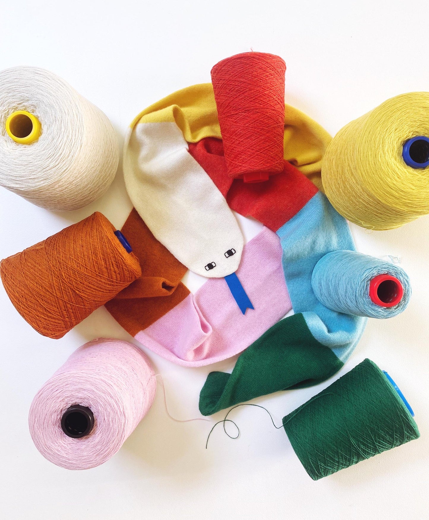 Colorful yarn spools arranged in a circular pattern on a white background