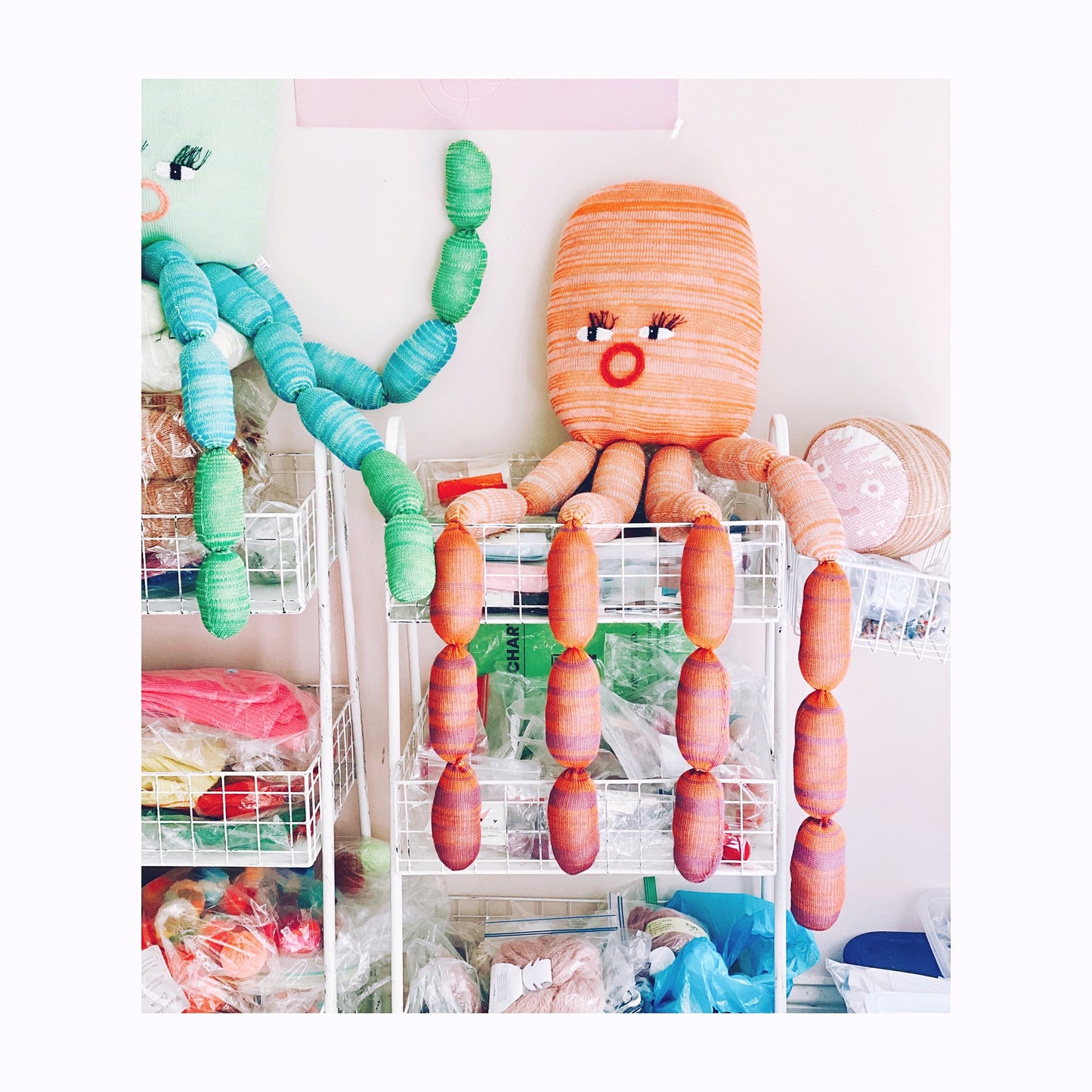 Colorful knitted octopus soft sculpture  in a room with shelves and items.