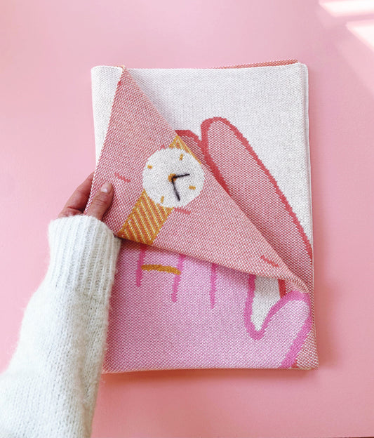 Person holding a pink and white knitted fabric on a pink background