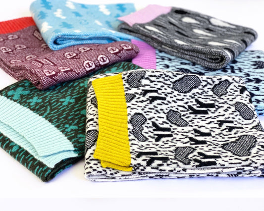 Collection of patterned knitted scarves in various colors on a white background