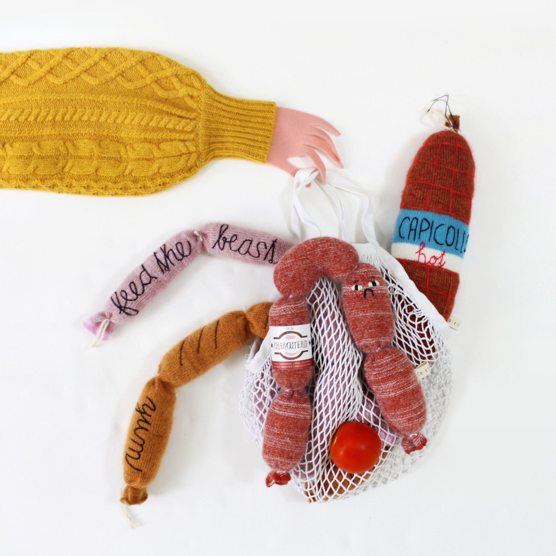 Knitted sausages in a mesh bag with a mustard yellow sweater on a white background