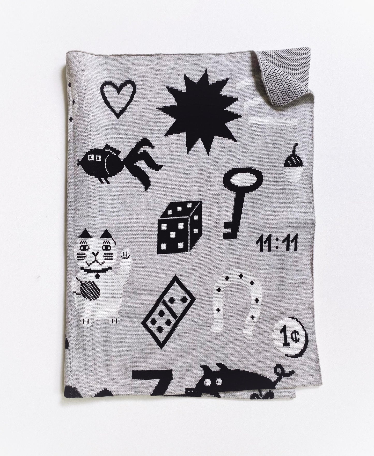 Gray knit blanket with black and white good luck charm symbols pattern on a white background