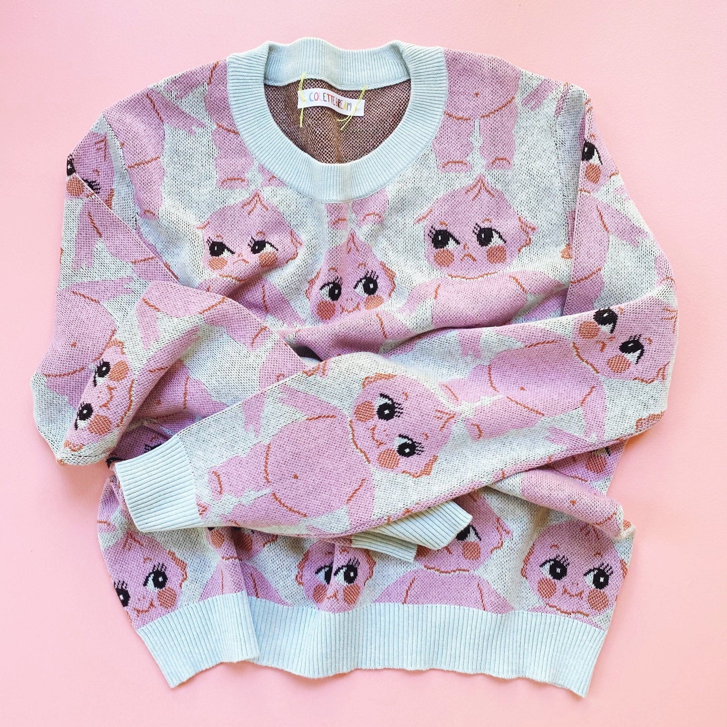 Pink sweater with kewpie doll pattern on a pink background