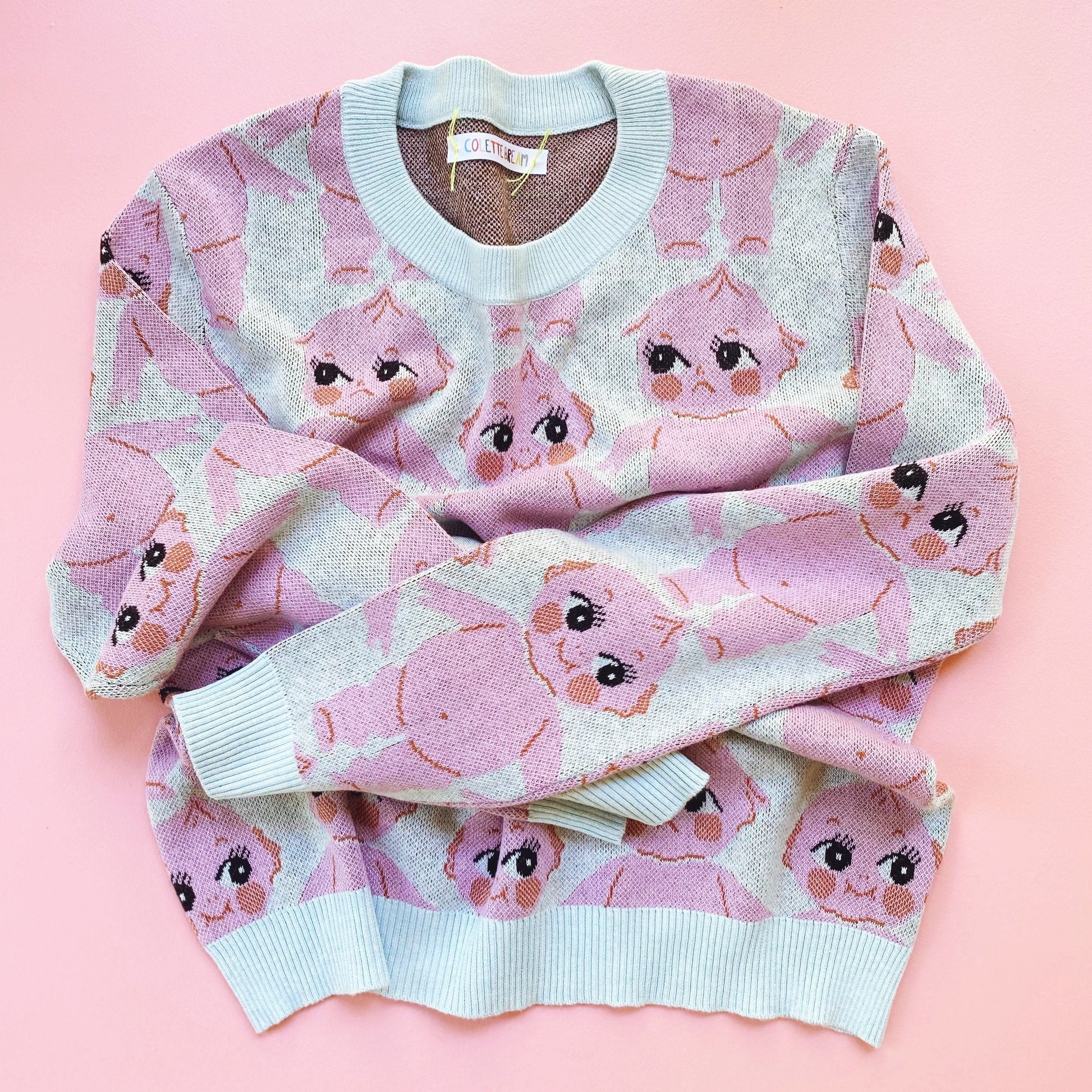 Pink sweater with kewpie doll pattern on a pink background