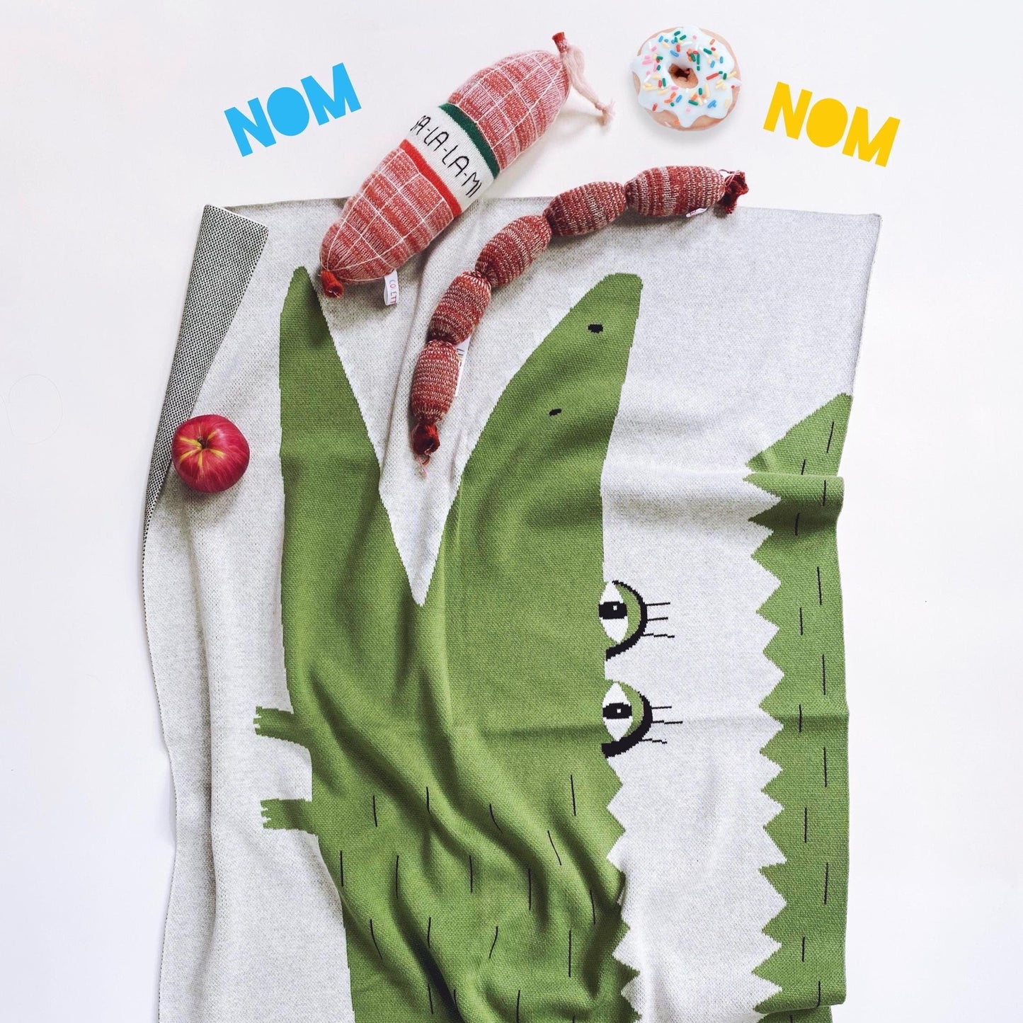 Knit baby blanket with a cartoon alligator design on a white background