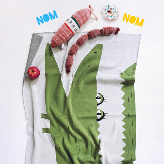 Knit baby blanket with a cartoon alligator design on a white background