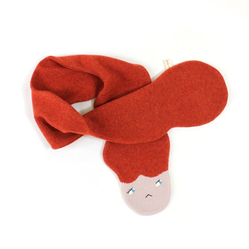 Red knitted lambswool scarf with a face on a white background
